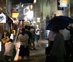 歓楽街で雨のシーンを撮影する様子の写真