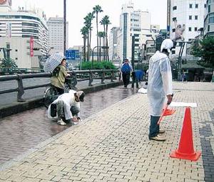 道路に水たまりが残らないように雑巾がけをする様子の写真